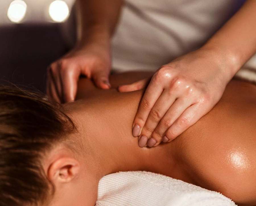A therapist massaging a person's upper back and shoulder